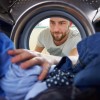 Man Doing Laundry Reaching Inside Washing Machine